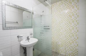 ein weißes Bad mit einem Waschbecken und einer Dusche in der Unterkunft Tongyeong V Motel in Tongyeong