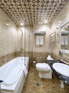 uma casa de banho com uma banheira, um WC e um lavatório. em GRAND HOTEL SOGDIANA em Samarkand