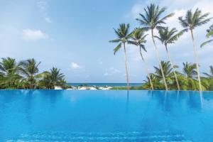 einen Pool mit Palmen und dem Meer in der Unterkunft Riu Sri Lanka All Inclusive in Bentota