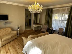 1 dormitorio con cama, sofá y lámpara de araña en Steenkoppies semi self catering apartment en Magaliesburg
