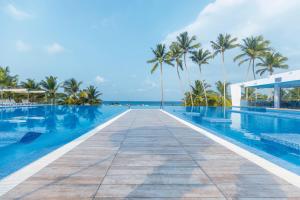 a swimming pool with palm trees and a boardwalk at Riu Sri Lanka All Inclusive in Bentota
