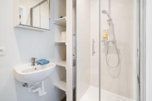 uma casa de banho branca com um lavatório e um chuveiro em Antwerp Center Cozy Cityflats em Antuérpia