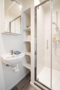 uma casa de banho branca com um lavatório e um chuveiro em Antwerp Center Cozy Cityflats em Antuérpia