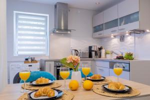 een tafel met 2 glazen sinaasappelsap en croissants bij Gelbe Koffer - Design-Apartment in Schiffweiler - Self-Check-in - 2 Parkplätze - WLAN - Balkon mit Gartenzugang - private Terrasse - ruhig gelegen - Nähe See & Wald - bis 4 Pers in Schiffweiler