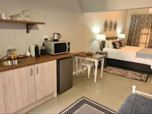 ein Hotelzimmer mit einem Bett und einer Küche mit einem Schreibtisch in der Unterkunft Steenkoppies semi self catering apartment in Magaliesburg