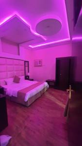 1 dormitorio con cama e iluminación rosa en شاليهات قمرا, en Qarār