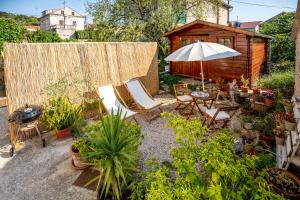 a garden with chairs and an umbrella and a cabin at Stone House Harmony in Korčula