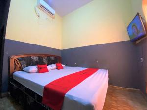 a bedroom with a bed with red pillows on it at RedDoorz @ Wisma Sentosa Palopo in Palopo