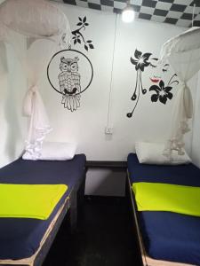 two beds in a room with a monkey on the wall at Cozy House Hostel in Ella