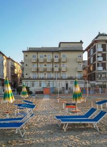 un gruppo di sedie a sdraio e ombrelloni sulla spiaggia di Hotel Nautic a Rimini