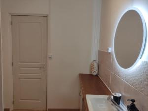 uma casa de banho com um lavatório, um espelho e uma porta em La Saint Quentinoise (avec cour) em Saint-Quentin