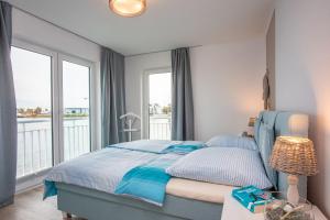sypialnia z niebieskim łóżkiem i balkonem w obiekcie Villa SeeZeit w mieście Kappeln