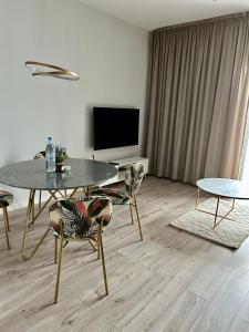 a living room with a table and chairs and a television at Golden Apartment Lodz, Zdrowie in Łódź