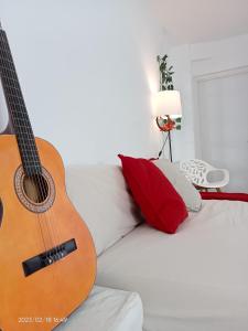 una guitarra sentada en un sofá en un dormitorio en Luminosa habitación, en Sevilla