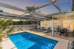 Modern Fort Lauderdale Pool Home في فورت لاودردال: مسبح على فناء مع كراسي وطاولة