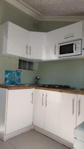 a kitchen with white cabinets and a microwave at uMzimhlophe in Port Shepstone +21 photos