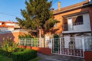 Casa de ladrillo con balcón y árbol en Barát Vendégház - Cosy Guesthouse - Teljes ház privát udvarral - 4 szoba, 2 fürdő, en Szeged