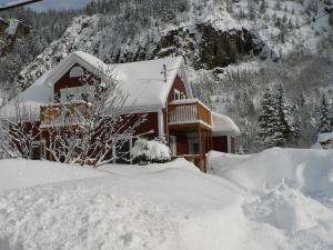 a house covered in snow in front of a mountain at B&B Les Deux Pignons in Petit-Saguenay