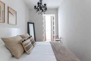 um quarto branco com uma cama com almofadas e um lustre em Coqueto y Tranquilo en el Centro em Bilbao