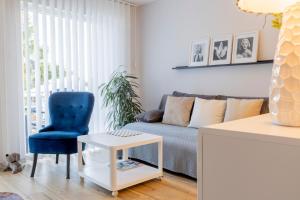 een woonkamer met een bank en een blauwe stoel bij Gelbe Koffer - Design-Apartment in Schiffweiler - Self-Check-in - 2 Parkplätze - WLAN - Balkon mit Gartenzugang - private Terrasse - ruhig gelegen - Nähe See & Wald - bis 4 Pers in Schiffweiler
