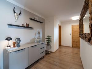 a kitchen with white cabinets and a wooden floor at Das Karl Appartement in Söll +9 photos