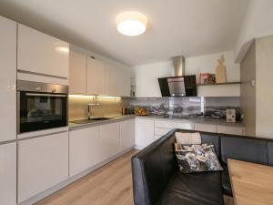 a kitchen with white cabinets and a black couch at Das Karl Appartement in Söll
