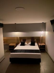 HOTEL ESTADIO DORADO في ميديلين: غرفة نوم بسرير كبير وطاولتين