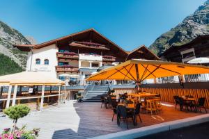 a restaurant with tables and umbrellas in front of a building at Hotel Mittagskogel Pitztal in Sankt Leonhard im Pitztal