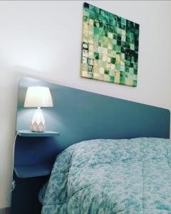 1 dormitorio con 1 cama con cabecero azul y lámpara en Colori del Belice appartamento, en Santa Ninfa