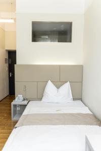 Bett mit weißen Kissen in einem Zimmer in der Unterkunft Kaiser von Österreich, Historik- und Thermalhotel in Bad Radkersburg