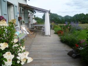 een houten loopbrug naar een patio met bloemen bij La Freneraie in Paulhac