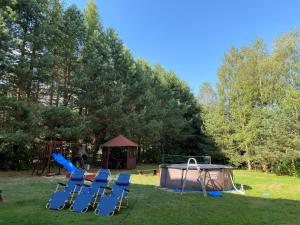 eine Gruppe von Stühlen und ein Spielplatz im Hof in der Unterkunft Domek Letniskowy Zacisze Guciów in Guciów