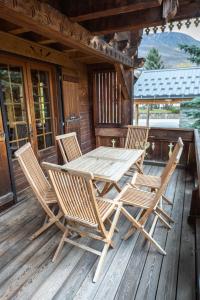 a wooden table and chairs on the porch of a cabin at Chalet Luxe Les Orchis Alpe d'Huez in LʼHuez
