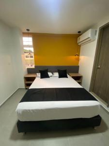 a bedroom with a large bed with a yellow wall at HOTEL ESTADIO DORADO in Medellín