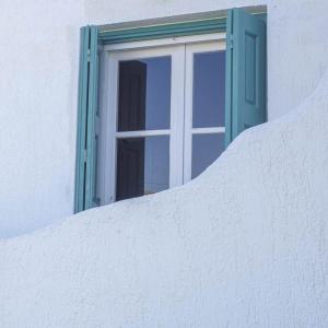 una ventana en el lateral de un edificio blanco en Anemoessa Studios en Pollonia