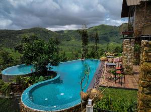 Ein Swimmingpool mit einem Berg im Hintergrund in der Unterkunft Tea & Tranquility by Moksha Stays in Vagamon