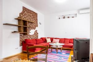 een woonkamer met een rode bank en een bakstenen muur bij Sofia's Vintage Gem: Spacious 2BD Flat on Solunska in Sofia