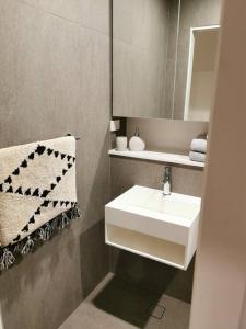 a bathroom with a white sink and a mirror at Urban Oasis: Central Wollongong in Wollongong