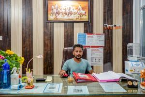 a man sitting at a desk in an office at Hotel Welcome Sri Vip Road Raipur in Phundardih