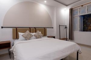 a bedroom with a large white bed and a window at Lynk Stay Hoian in Hoi An