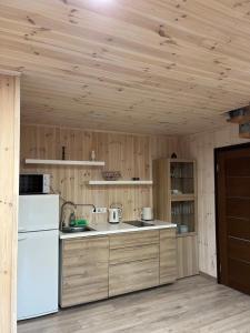 uma cozinha com um frigorífico branco e paredes de madeira em Atostogų namelis em Kurėnai