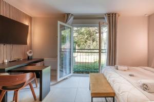 1 dormitorio con cama, escritorio y ventana en La Parisienne, en Palaiseau