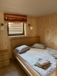 Cama en habitación de madera con ventana en Atostogų namelis en Kurėnai