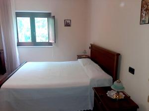 1 dormitorio con cama blanca y ventana en RESIDENZA RURALE L'ANTICO CASTAGNETO, en Sicignano degli Alburni