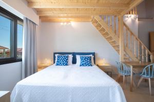 una camera da letto con un letto con cuscini blu e una scala di Zisis Suites a Nydri Altre 37 foto