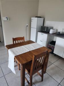 a kitchen with a wooden table with two chairs and a refrigerator at Guesthouse 71 King Size Guest Room in Boksburg