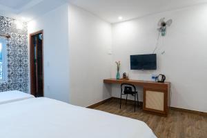 um quarto com uma cama e uma secretária com uma televisão em Lynk Stay Hoian em Hoi An
