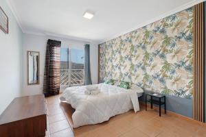 1 dormitorio con cama y pared con papel pintado tropical en Duplex Tejita Beach, en Granadilla de Abona