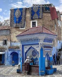 una mujer parada frente a un edificio azul en Casa Fahssi, en Chefchaouen