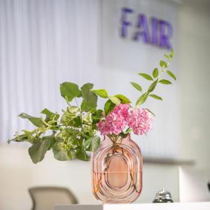 ブルノにあるFairhotelのテーブルの上にピンクの花が咲き誇るガラスの花瓶